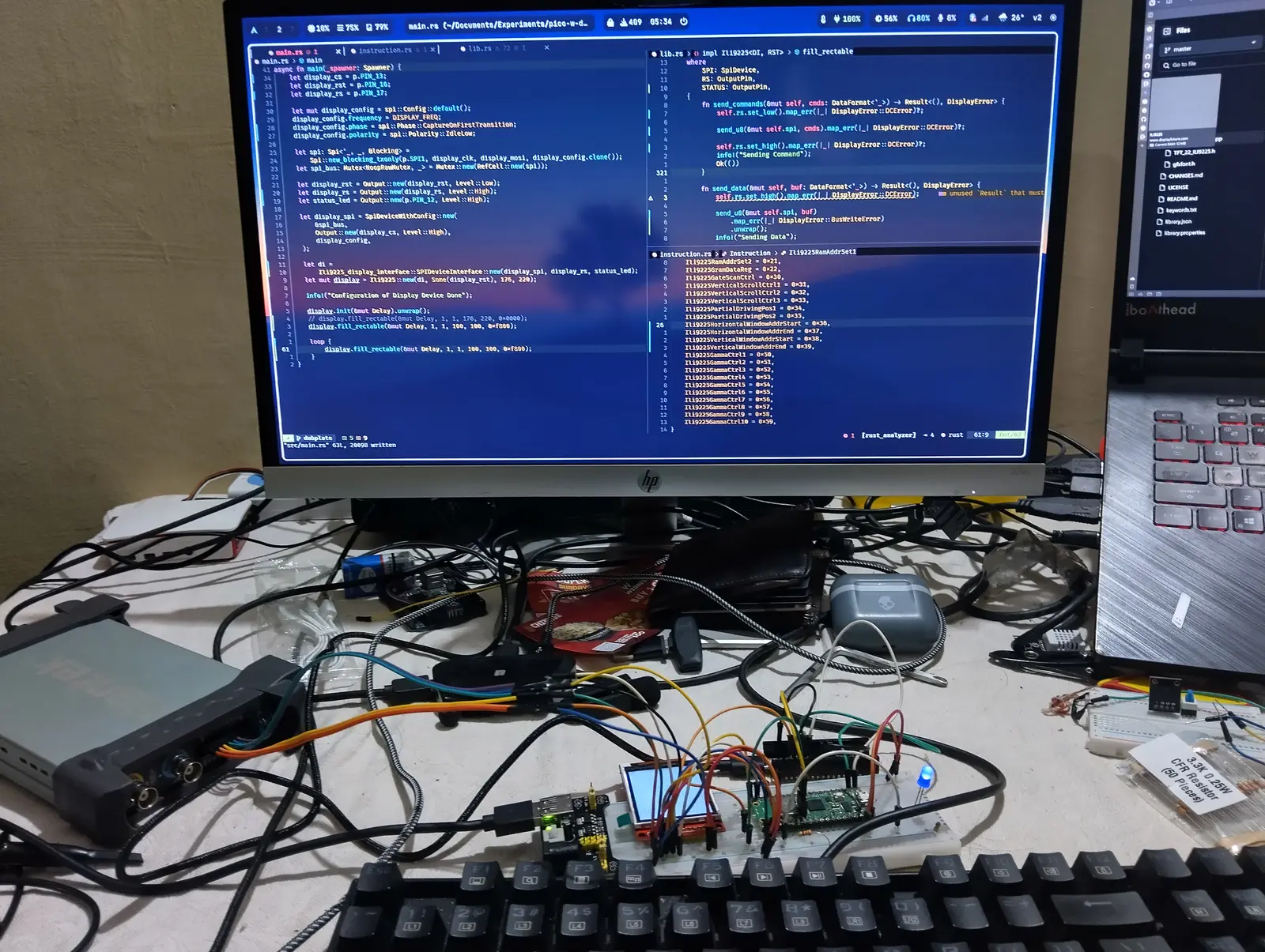 Writing an ILI9225 SPI display driver in Rust for the Pico — source on the monitor, the display itself wired up on the desk.